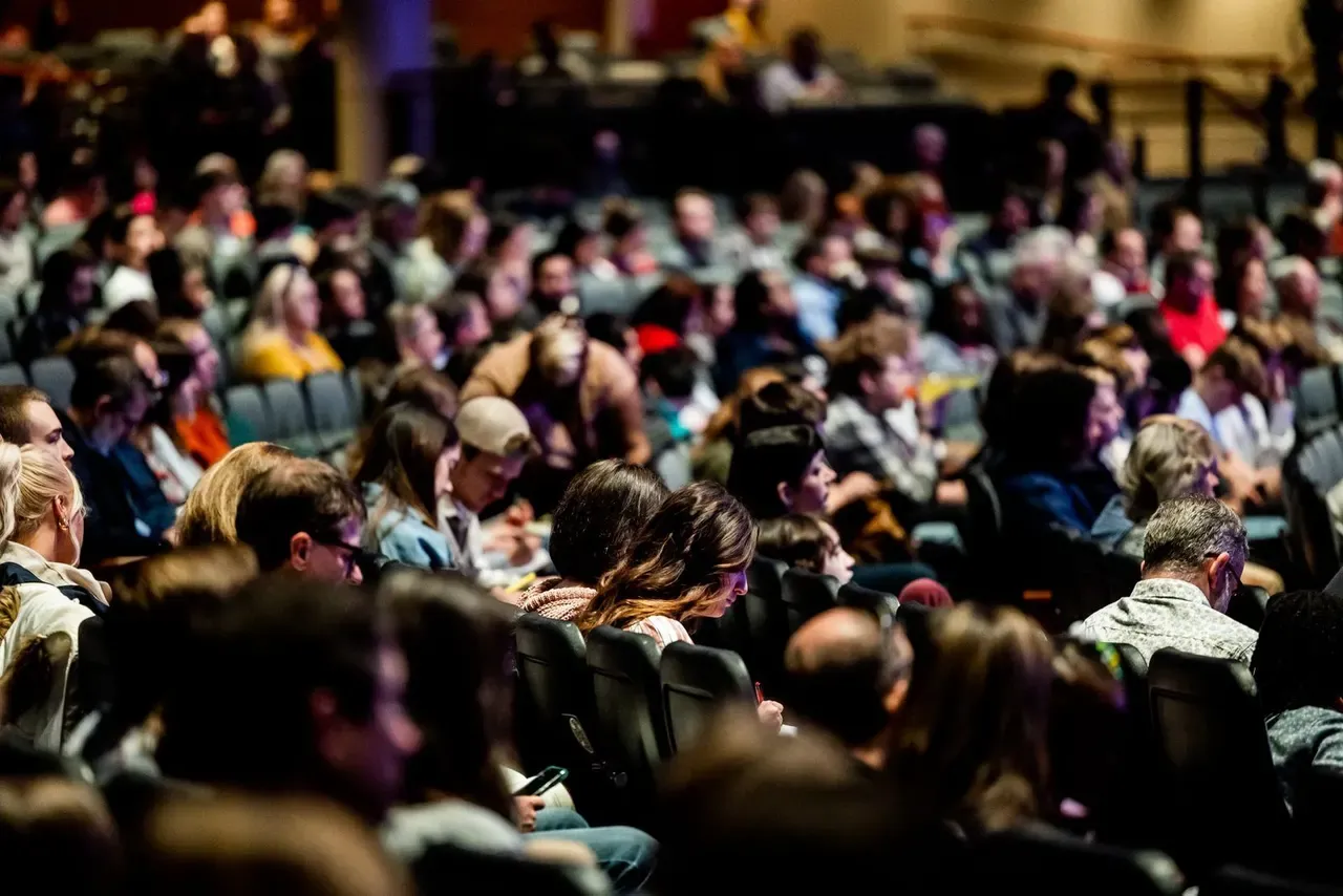 A crowded lecture theatre, the seated audience out of focus