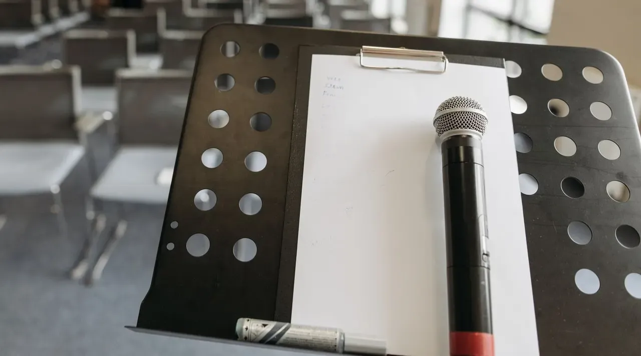 A microphone resting on a lectern beside a notepad and pen before an event begins