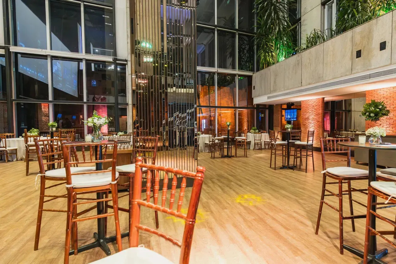 A function space at night, glass walls and warm lighting, laid out with high tables and chairs
