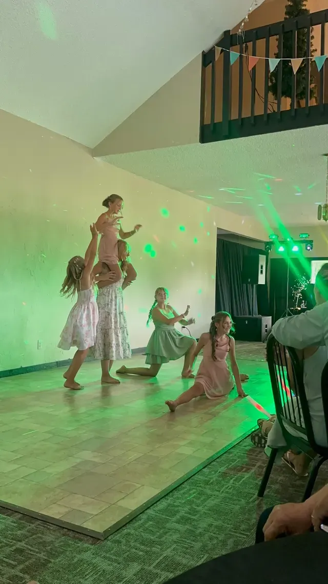 Children dancing under green stage lighting at a wedding reception