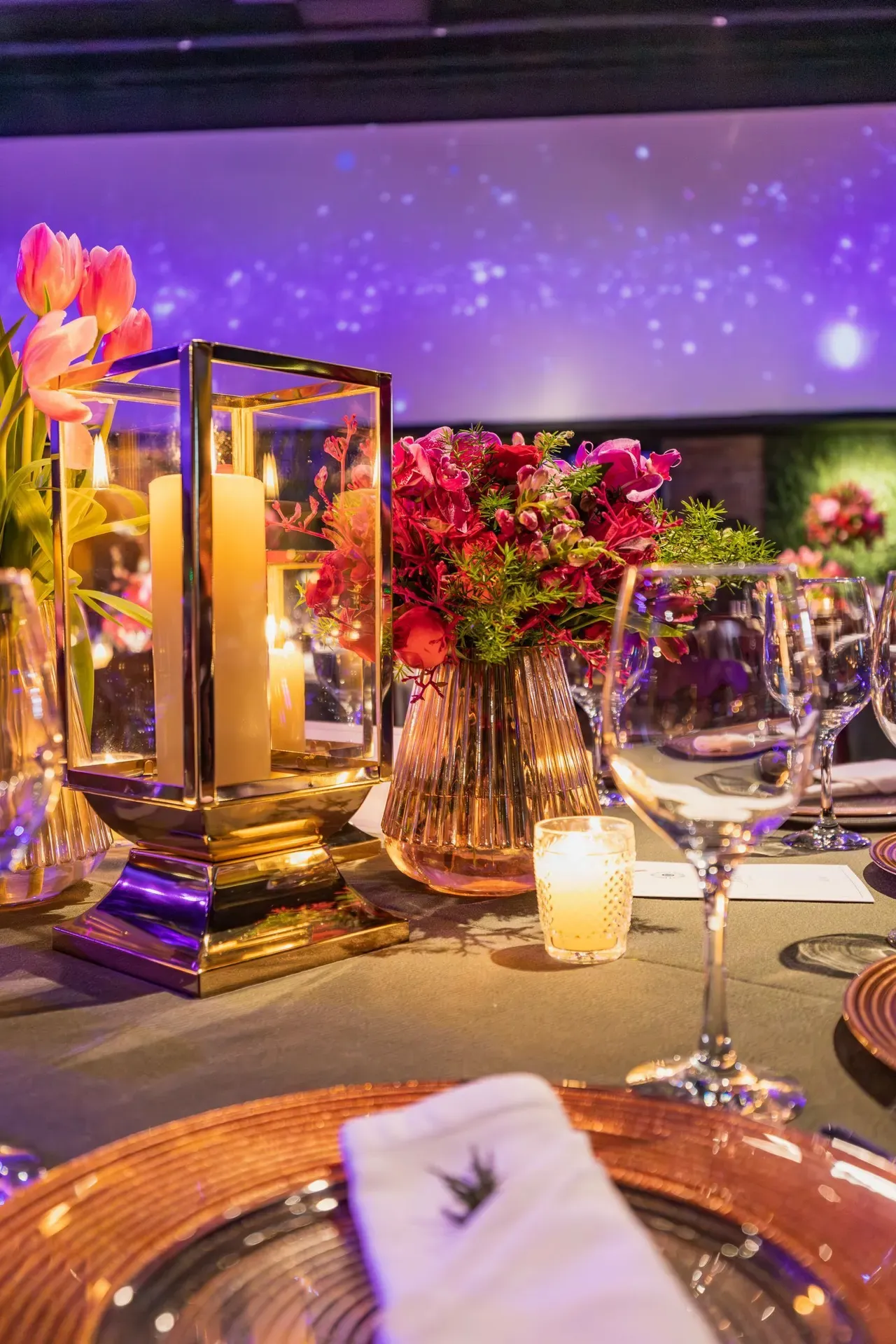 A table set for a formal dinner, candles and flowers in gold and deep red